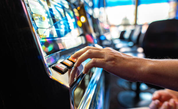 Closeup of Gambler Pressing the Spin Button While Playing Slot Machine in the Casino. Gambling Industry Theme.