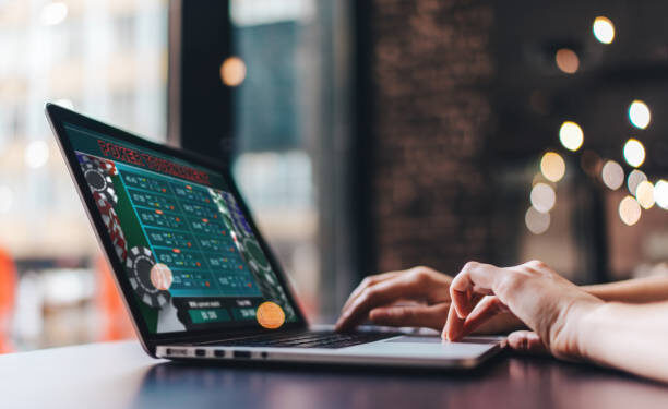 Close up cropped photo of girl hands using her laptop for taking part in online poker tournament.