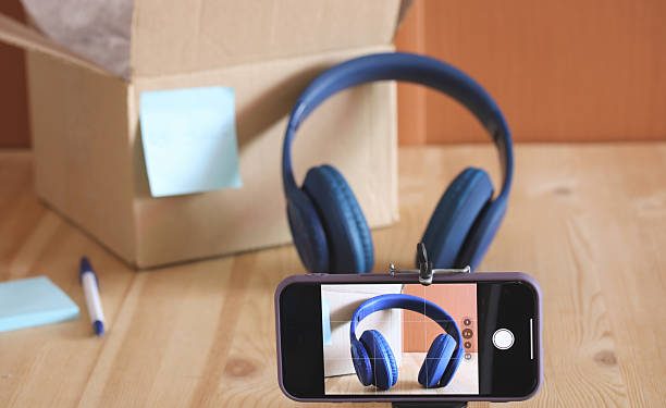 New blue wireless headphones are being photographed with a smartphone for an online shop or ecommerce platform